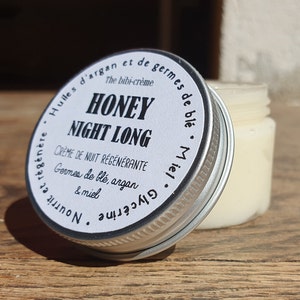 May include: A silver jar with a white label that reads "Honey Night Long Creme de Nuit Regenerante Germes de ble, argan & miel Glycerine  Nourrit et regenere Huiles d'argan et de germes de ble Miel".