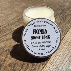 May include: A white jar with a silver lid labeled "Honey Night Long" with the text "The bibi-cr&egrave;me Cr&egrave;me de nuit r&eacute;g&eacute;n&eacute;rante Germes de bl&eacute;, argan & miel Huiles d'argan et de germes de bl&eacute;. Miel Glyc&eacute;rine et Nourrissante"