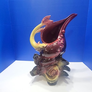 May include: A white ceramic mug with a black handle and the text "But First, Coffee" in a black, bold font. The mug is sitting on a wooden surface. The mug is approximately 4 inches tall.