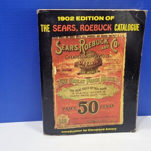 Może przedstawiać: Zabytkowe wydanie katalogu Sears, Roebuck z 1902 roku. Okładka jest czarna z czerwoną i zieloną reklamą "Cheapest Supply House on Earth". Cena to 50 centów. To historyczny przedmiot.