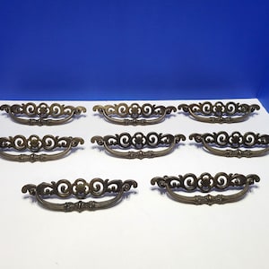 May include: Eight antique brass cabinet drawer pulls with a decorative scroll design.