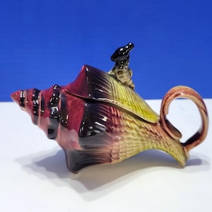 May include: A white ceramic mug with a black handle and the text "But First, Coffee" in a black, bold font. The mug is on a white surface.