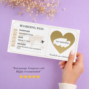 May include: A white boarding pass with gold accents, featuring a heart-shaped scratch-off area. The pass includes the text "BOARDING PASS", passenger details, date, and a message. A small airplane graphic is also present.