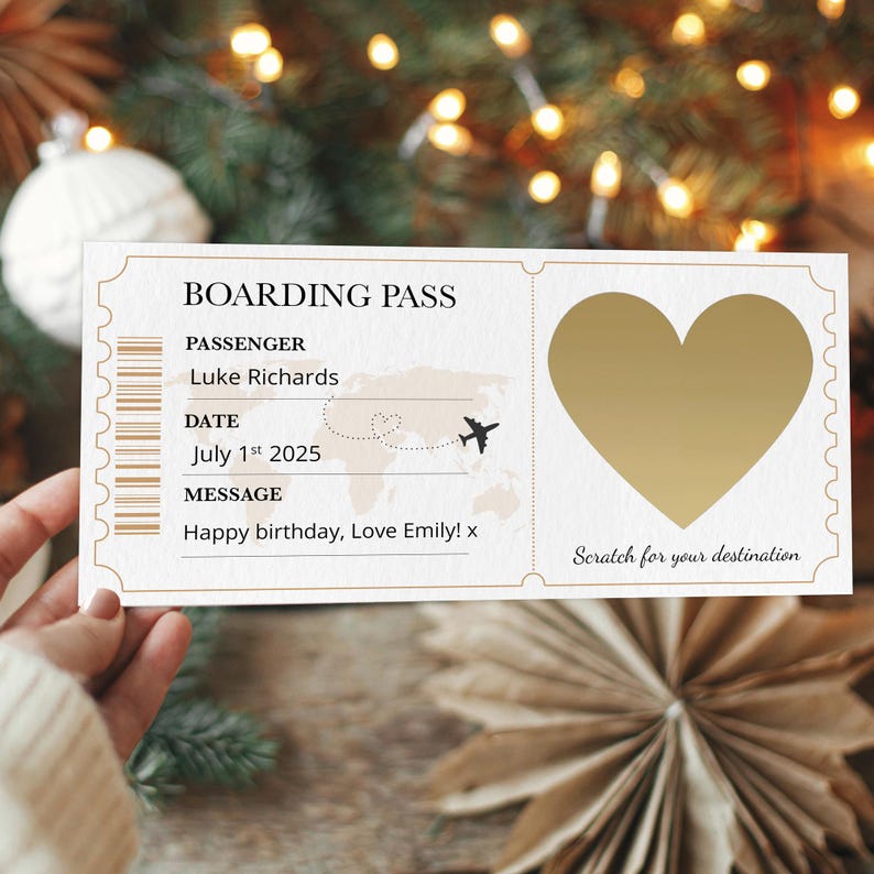 May include: A boarding pass design with a gold heart scratch-off area. The text includes "BOARDING PASS", "PASSENGER: Luke Richards", "DATE: July 1st 2025", and a birthday message. The background is blurred with festive lights.