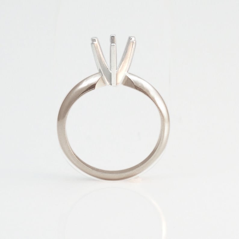 May include: A silver ring with a prong setting for a center stone.