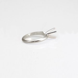 May include: A silver ring setting with a prong setting for a solitaire diamond.