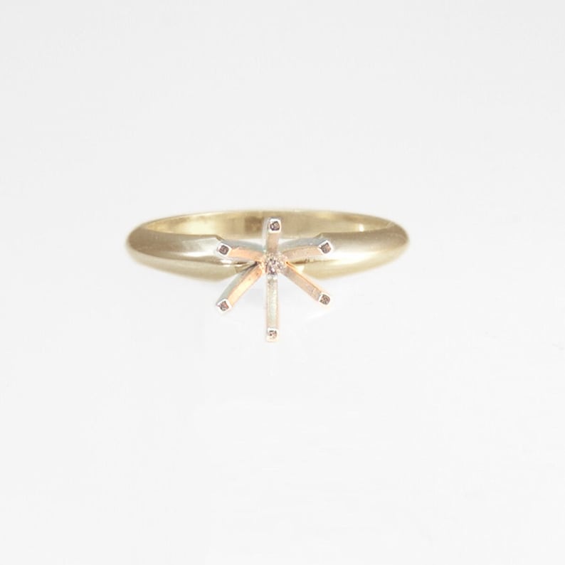 May include: A gold ring with a six-prong setting for a center stone.