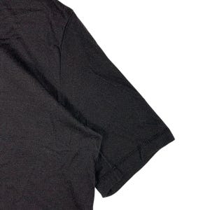 May include: A plain black short-sleeved t-shirt made of a soft, lightweight fabric. The garment features a simple crew neckline and standard stitched hems on the sleeves and body, showcasing a solid, uniform dark color throughout the entire piece.