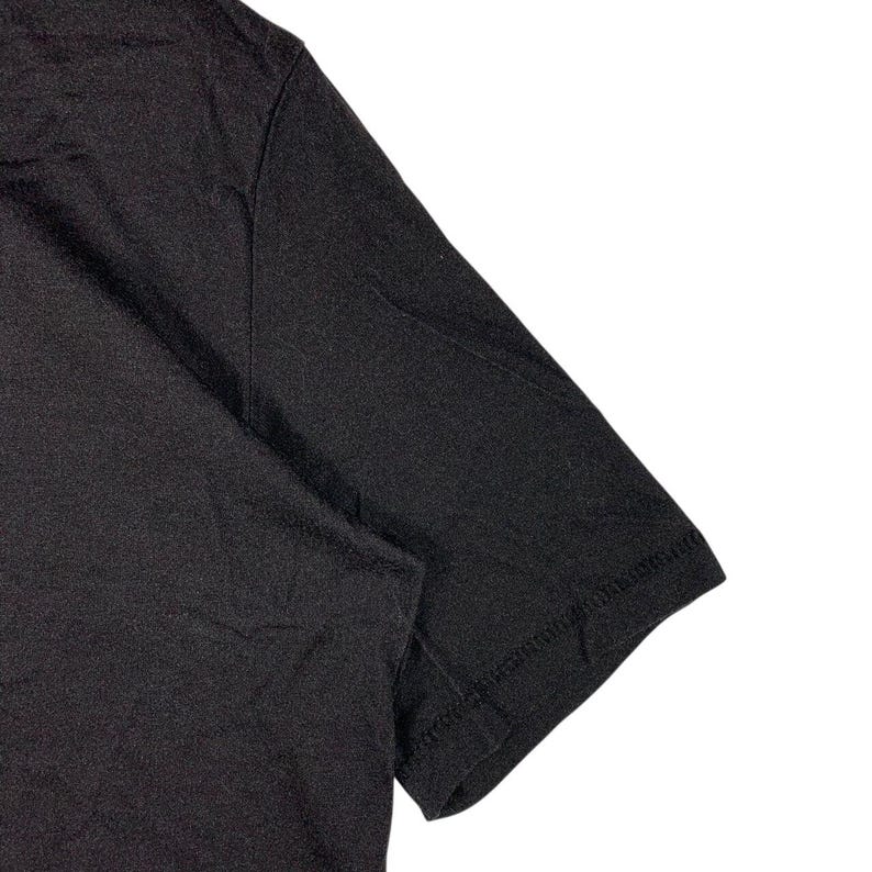 May include: A plain black short-sleeved t-shirt made of a soft, lightweight fabric. The garment features a simple crew neckline and standard stitched hems on the sleeves and body, showcasing a solid, uniform dark color throughout the entire piece.