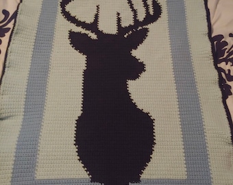 May include: A crocheted blanket with a blue and green border and a black silhouette of a deer with antlers in the center. The blanket is on a bed with a floral pattern. The text "Customer Photo!!" is at the bottom of the image.