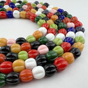 May include: A colorful glass bead necklace with a variety of colors, including red, green, blue, white, and black. The beads are all different shapes and sizes, and they are strung together on a clear string.