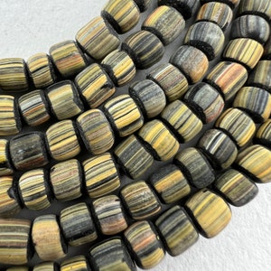 May include: A close-up of a strand of black and yellow striped glass beads. The beads are cylindrical and have a slightly rounded shape. The stripes are thin and evenly spaced.