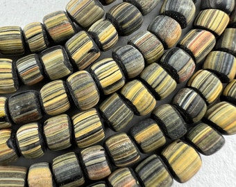 May include: A close-up of a strand of black and yellow striped glass beads. The beads are cylindrical and have a slightly rounded shape. The stripes are thin and evenly spaced.