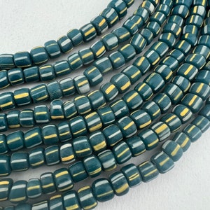 May include: A strand of teal blue glass beads with white and yellow stripes. The beads are cylindrical and have a matte finish.