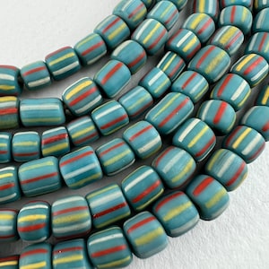 May include: A strand of blue, white, yellow and red striped glass beads. The beads are cylindrical and have a matte finish.