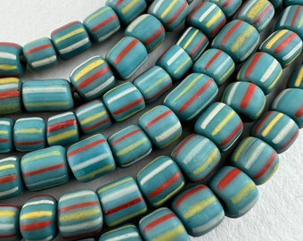May include: A strand of blue, white, yellow and red striped glass beads. The beads are cylindrical and have a matte finish.