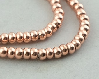May include: A strand of rose gold beads, each bead is round and smooth. The beads are strung together to form a continuous chain.