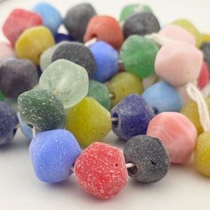 May include: A strand of colorful, textured beads in various shapes and sizes. The beads are in shades of red, yellow, green, blue, pink, and black. The beads are strung together with a white string, creating a vibrant and eye-catching accessory.