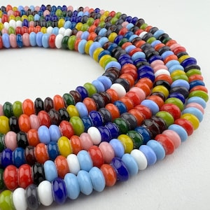 May include: A colorful assortment of glass beads in various shades of blue, red, green, yellow, and white. The beads are arranged in a circular pattern, creating a visually appealing and vibrant display.