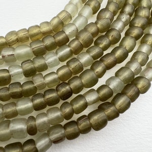 May include: A strand of light green and dark green glass beads. The beads are round and have a slightly frosted finish.