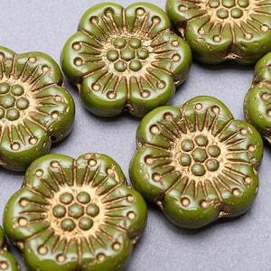 May include: Green glass flower beads with gold accents. The beads have a five-petal flower design with a raised center.