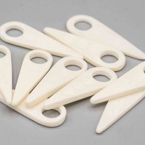 May include: A set of ten white plastic tools for removing the stems from grapes. The tools are shaped like a small, pointed spade with a hole in the handle.