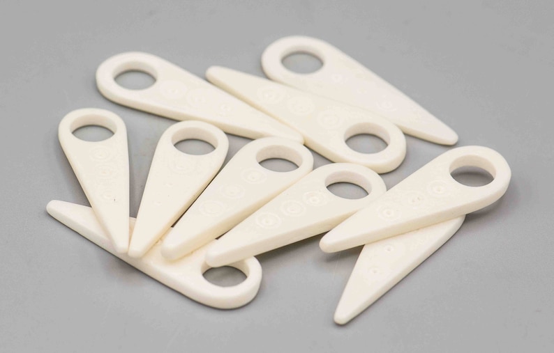 May include: A set of ten white plastic tools for removing the stems from grapes. The tools are shaped like a small, pointed spade with a hole in the handle.