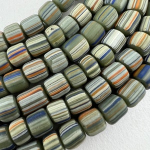 Puede incluir: Una hebra de cuentas de vidrio rayadas en verde, blanco, azul y naranja. Las cuentas son cilíndricas y tienen una forma ligeramente irregular.