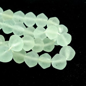May include: A strand of light green glass beads, each bead is faceted and has a slightly frosted finish.