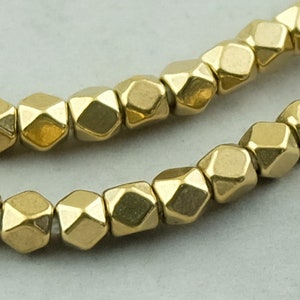 May include: A strand of gold-colored faceted beads. The beads are shaped like small, irregular hexagons.
