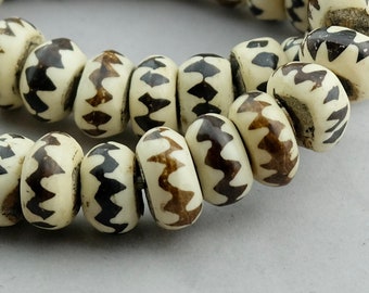 May include: A strand of white beads with brown zig-zag patterns. The beads are round and have a smooth, polished finish.