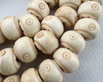 May include: A strand of white bone beads with a carved circular design. The beads are smooth and have a natural, off-white color.