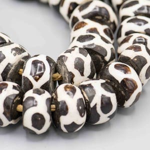 May include: A strand of black and white patterned beads. The beads are round and have a smooth, polished finish.