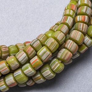 May include: A strand of green, white and orange striped glass beads. The beads are round and have a slightly irregular shape.