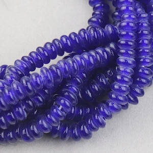 May include: A strand of deep blue glass beads with a slightly frosted finish. The beads are round and have a slightly irregular shape, giving them a unique and handmade look.