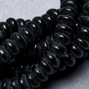 May include: A close-up of a black spiral hair tie made of multiple small, connected rings.