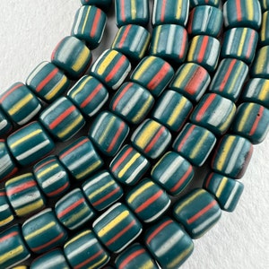 May include: A collection of teal blue glass beads with white, yellow, and red stripes. The beads are cylindrical in shape and have a matte finish.
