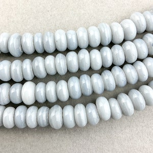 May include: A strand of light gray agate beads with a smooth, polished finish. The beads are round and have a slightly irregular shape.