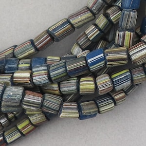 May include: A strand of colorful glass beads with a striped pattern. The beads are a mix of blue, green, yellow, and brown.