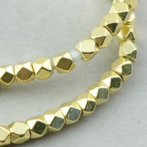 May include: A strand of gold-colored faceted beads. The beads are small and have a geometric shape.