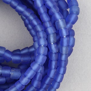 May include: A close-up of a strand of blue glass beads. The beads are small and have a matt finish.