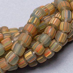 May include: A strand of colorful glass beads with a striped pattern. The beads are translucent and have a light green hue. The beads are stacked on top of each other, creating a layered effect.
