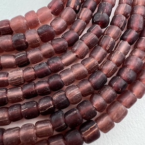 May include: A strand of dark purple glass beads with a frosted finish. The beads are round and have a slightly irregular shape.