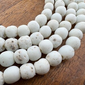 May include: A strand of white, round, natural stone beads. The beads are smooth and have a slightly textured surface.