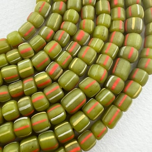 May include: A strand of green glass beads with white and orange stripes. The beads are round and have a smooth, polished finish.