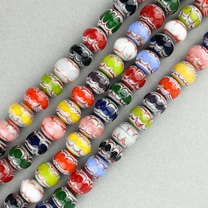 May include: A strand of colorful glass beads with intricate white patterns. The beads are round and have a glossy finish.