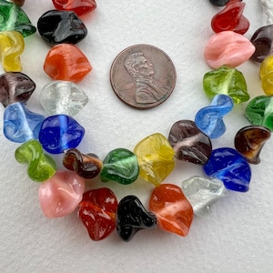 May include: A strand of colorful glass beads, some with swirls and patterns, in various shapes and sizes. The beads are strung on a clear cord and are arranged in a random order. The beads are approximately the size of a US penny.