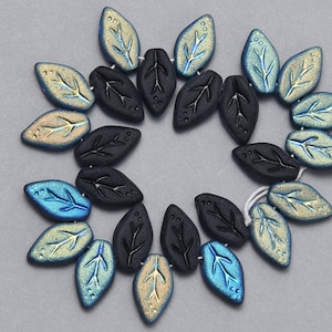 May include: A strand of black and iridescent glass beads in the shape of leaves. The beads have a textured surface and are strung on a white thread.