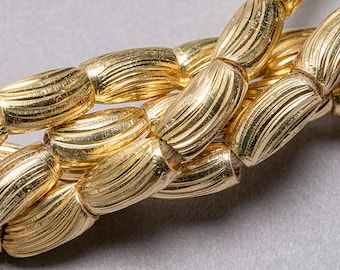May include: A close-up of a gold chain necklace with a textured, ribbed design. The chain is made of multiple strands of linked beads.