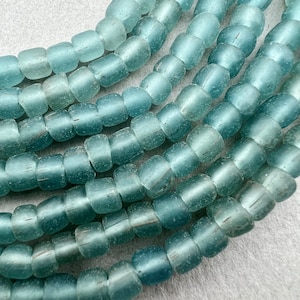 May include: A strand of light blue glass beads. The beads are round and have a frosted finish.